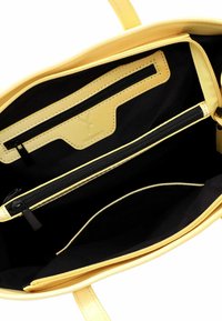 Interno della borsa gialla con fodera nera. Presenta una tasca con cerniera e una tasca a scomparsa, texture liscia e dettagli cuciti lungo le cuciture.
