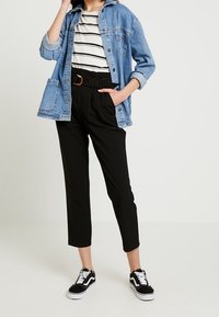 Džínová bunda, pruhované tričko, černé zužující se kalhoty a černé tenisky. Výrazné prvky: volný střih, zapínání na knoflíky, pas ve střední výšce a opasek.