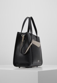Černá texturovaná kožená kabelka se strukturálním tvarem, kontrastním béžovým akcentem a krátkými rukojeťmi. Obsahuje malou zipovou kapsu.