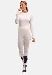 Tuta termica bianca a maniche lunghe dal design aderente, texture liscia e dettagli grigi a contrasto su gambe e caviglie.