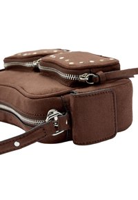 Brązowa torba zamszowa z dwoma zamykanymi na zamek komorami, srebrnym wykończeniem i ozdobnymi ćwiekami. Posiada płaskie dno i regulowany pasek.