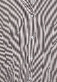 Camicia con bottoni, a strisce verticali marroni e bianche, realizzata in tessuto leggero; presenta bottoni bianchi e un colletto.