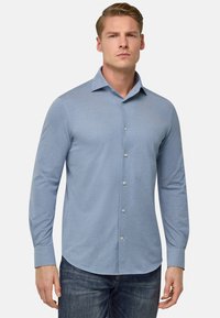 Camicia azzurra a maniche lunghe con bottoni, realizzata in tessuto morbido, con colletto appuntito, texture sottile e orlo arrotondato.