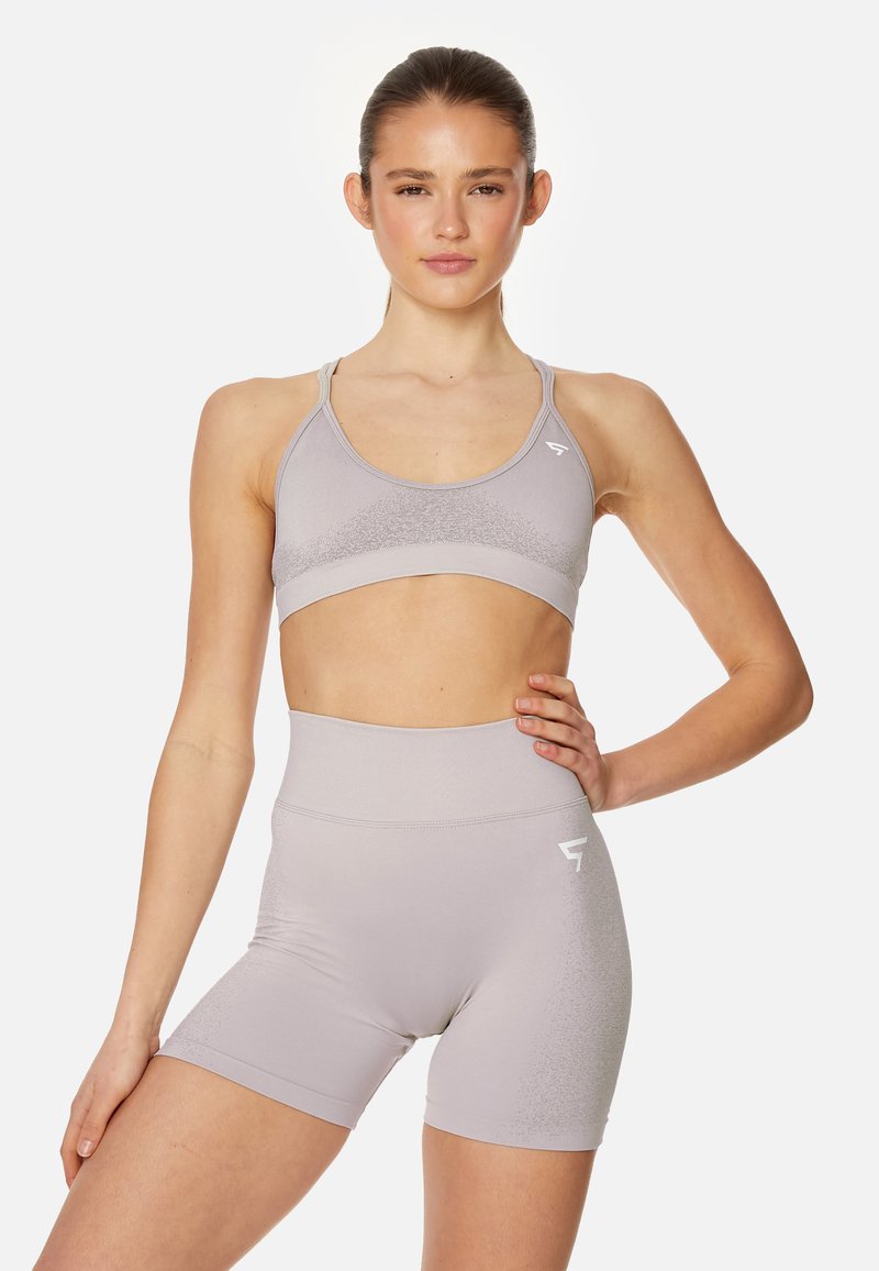 Set di reggiseno sportivo grigio chiaro e pantaloni corto a vita alta. Texture liscia con una silhouette aderente. Motivo a gradiente sottile, dettagli di branding minimi.