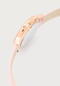 Κουτί ρολογιού σε ρόζ χρυσό με ροζ δερμάτινο λουρί, που εμφανίζει το πλευρικό κουρδιστήρι και το πίσω καπάκι πάνω σε λευκό φόντο.