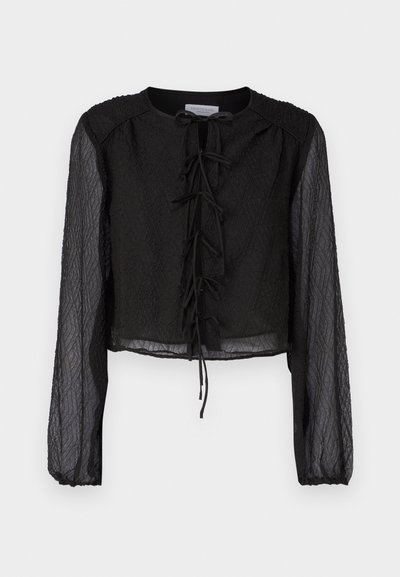 Melnā kroķēta blouse, izgatavota no teksturēta auduma, ar garām caurspīdīgām piedurknēm, apaļu kakla izgriezumu un priekšējo saiti.