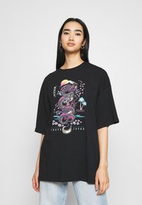 Svart oversized t-skjorte med et fargerikt dragegrafikk med kirsebærblomster og solnedgang, laget av bomull med en avslappet passform.