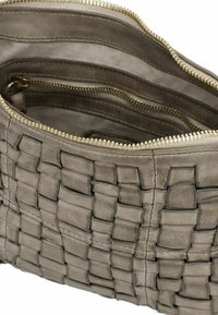 Borsa a tracolla in pelle intrecciata di un grigio tenue con superficie testurizzata. L'interno è foderato in tessuto e presenta un comparto con cerniera. Cerniera in tono dorato.