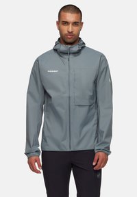Lett grå jakke med lynlåsfortil, justerbar hætte og brystlomme. Har elastiske manchetter og "Mammut"-logoet på brystet.