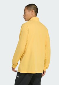 Lange mouwen gele shirt met een kraag en een relaxte pasvorm. Gemaakt van zacht stof, met minimale zichtbare branding nabij de zoom.