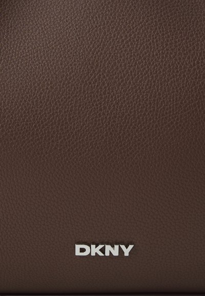 Sac en cuir brun texturé avec un logo "DKNY" argenté en bas, présentant une finition lisse et un motif de grain subtil.