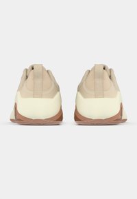 Baskets beiges avec une tige en maille texturée, une intercalaire crème rembourrée et une semelle en caoutchouc marron. Équipées d'une languette au dos.