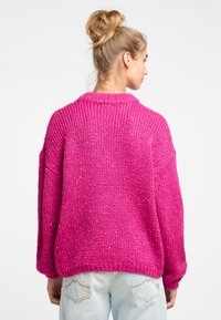 Maglione a maglia fucsia con vestibilità ampia, spalle scese e polsini a coste. Filato testurizzato con un brillantezza sottile; colletto ampio e arrotondato.