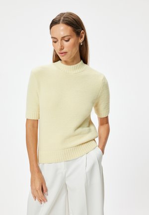 Pull à manches courtes, jaune pâle, en maille texturée. Il possède un col et un ourlet côtelés, avec une coupe décontractée.