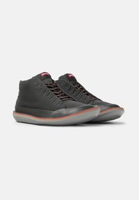 Gray high-top shoes made of soft leather, featuring a rubber sole with a red accent, and a unique stitched design on the upper.