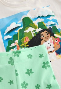 Cotton t-shirt with a colorful graphic featuring mountains, clouds, and a character, paired with mint green shorts adorned with dark green floral patterns.