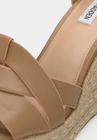 Sandale compensée nude avec semelle en jute tressé, brides en simili cuir lisse disposées en croisillon, avec des accents cousus et une étiquette de marque.