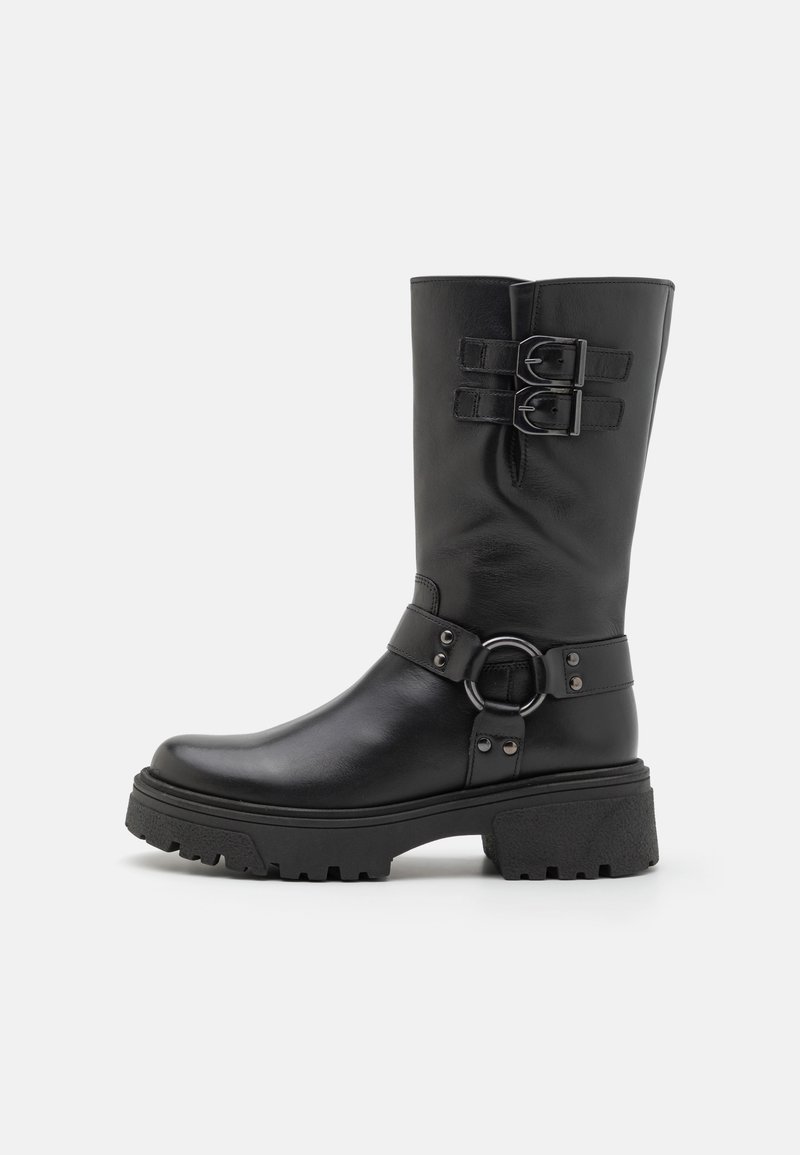 Bota de cuero negro hasta la rodilla con correas de doble hebilla, acento de hardware circular, suela robusta y textura suave; presenta una punta redondeada.