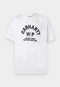 Λευκό κοντομάνικο T-shirt με στρογγυλή λαιμόκοψη, μαύρο κείμενο "CARHARTT WIP", ένα γράφημα με ένα χέρι που κρατά ύφασμα και το σύνθημα "HOLDING THINGS TOGETHER SINCE 1989".