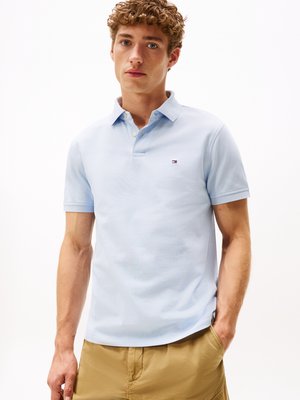 Polo shirt azzurro chiaro con colletto, maniche corte e un piccolo logo sul petto; abbinato a pantaloni corti khaki. Tessuto liscio.