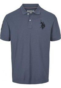 Modrá polokošile s krátkým rukávem a límečkem, se dvěma knoflíky a černým vyšitým logem hráče polo na levé hrudi.