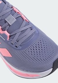 Baskets de sport lilas clair avec des accents roses, tige en mesh, système de laçage, texture perforée, languette rembourrée et semelle amortie.