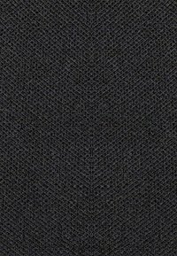 Tessuto intrecciato scuro con un motivo a spina di pesce, caratterizzato da una superficie texture. Il colore è prevalentemente nero con sottili variazioni.