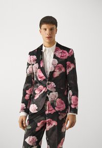Floral suit with a fitted design in black fabric, featuring large pink and white roses. Includes a white shirt underneath and button details.