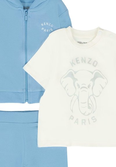 Felpa con cappuccio azzurro chiaro con zip e pantaloni della tuta abbinati, abbinati a una t-shirt bianca con una grafica di un elefante grigio e la scritta "KENZO PARIS".
