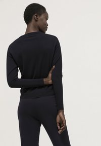 Marineblauer Langarmpullover von hinten, mit lockerem Schnitt, gerippten Bündchen und einem schlichten, unauffälligen Design.