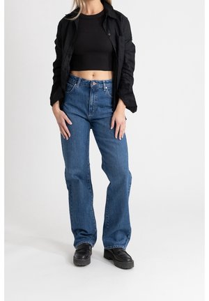 Blue flared jeans with a high waist, paired with a black cropped top and a black button-up shirt. Footwear is black platform shoes.