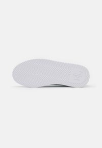 Suela de zapato de goma blanca con patrón de espiga y logotipo "RL" elevado cerca del talón sobre un fondo blanco liso.