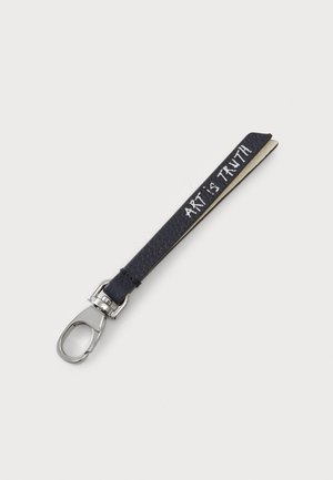 Porte-clé en cuir noir avec une finition texturée et un clip en argent. Présente un texte blanc portant la mention "L'ART EST LA VÉRITÉ" sur un côté.