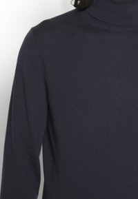 Maglione a collo alto navy realizzato in materiale a coste, con maniche lunghe e una silhouette aderente.