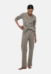 Ensemble de pyjama à imprimé léopard en beige et marron, comprenant une chemise boutonnée et un pantalon droit, réalisé en tissu doux avec une texture lisse.