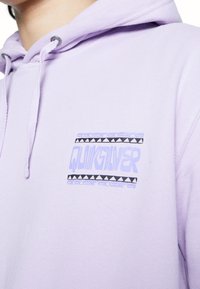 Lavendelfärgad hoodie med snörning och en framficka med en logotypprydnad som har geometriska mönster i svart och ljusblått. Mjuk textur, avslappnad passform.