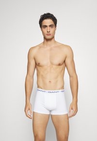 Witte katoenen boxershorts met een aansluitend ontwerp en een elastische tailleband met merk in marineblauw, met een gladde textuur en minimale stiksels.