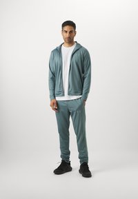 Under Armour RIVAL KNIT - Tracksuit - jasper blue/serpentine
