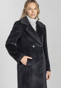 Podwójnie zapięty ciemnoszary wełniany płaszcz z szerokim kołnierzem, kieszeniami z przodu i granatowymi guzikami, charakteryzujący się miękkim, teksturowanym wykończeniem.