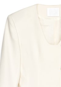 Valkoinen bleiseri, jossa on sileä rakenne, jämäkät hartiat ja syvä V-pääntie. Sisäpuolella lähellä kaulaa on huomaamaton etiketti.