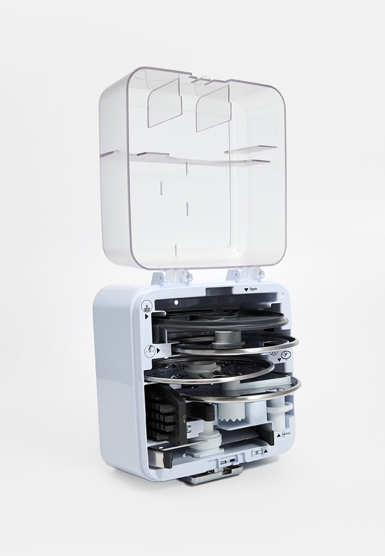 Un dispositif en plastique blanc avec un couvercle transparent, révélant des composants circulaires à l'intérieur, y compris des bobines et des engrenages, conçu pour un rangement compact.