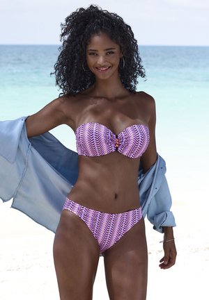 Lila- und rosa Bikini mit Zickzackmuster, mit einem trägerlosen Oberteil, das mit einem Knopfdetail akzentuiert ist; leichter blauer Überwurf.