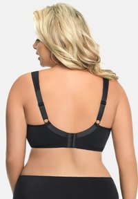 Svart bh med justerbara band, hyskopplås och mjukt tyg. Slät textur med subtila sömnadsdetaljer längs kanterna.