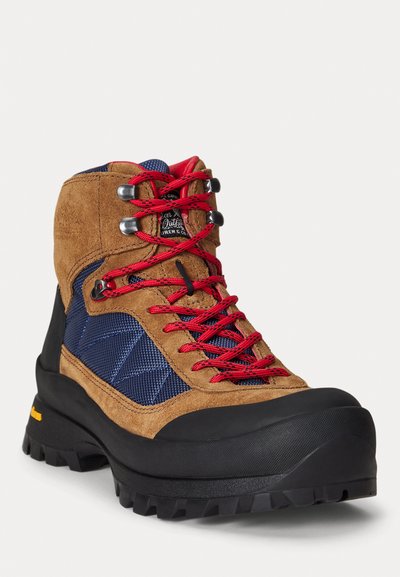 Scarpa da trekking in suede marrone e tessuto blu con lacci rossi, punta in gomma, suola texturizzata e occhielli in metallo. Marchio Vibram sulla suola.