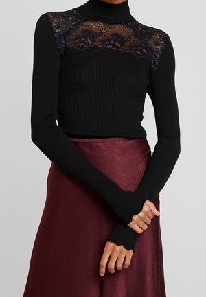 Top de cuello alto negro con textura acanalada, detalles de encaje transparente y patrones florales en los hombros, combinado con una falda larga de satén color burdeos.