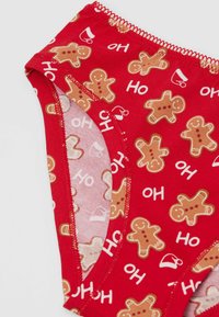 Biancheria intima rossa in cotone con motivi di omini di pan di zenzero e testo "Ho", con una texture morbida e liscia e bordi con cuciture a contrasto.