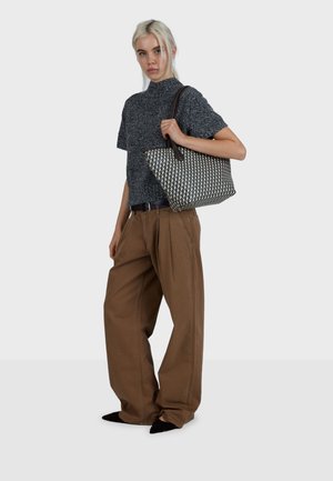 Geweven draagtas met een geometrisch patroon in zwart, crème en blauw; voorzien van bruine leren handvatten en een ruim ontwerp.