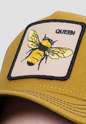 Cappello giallo con una patch quadrata che presenta un'ape ricamata e la parola "QUEEN" sopra di essa. Tessuto strutturato con visiera curva.