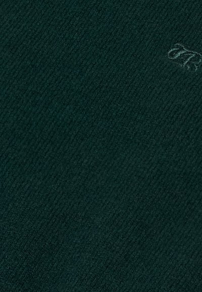 Ciemnozielony materiał w prążki z małym haftowanym szczegółem w postaci kursywnej litery w prawym górnym rogu.