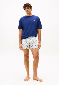 Camiseta azul de manga corta combinada con bóxer blancos con un patrón de anclas náuticas negras. Ajuste sencillo y casual; material de algodón.